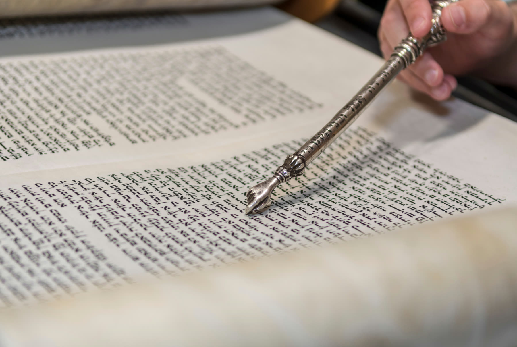 A yad pointing to the script of an open Sefer Torah